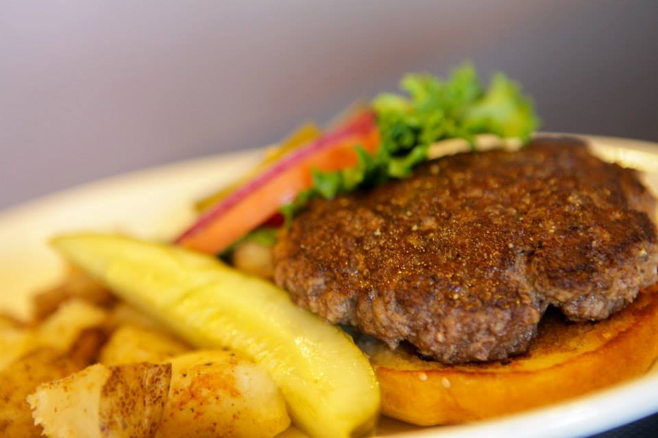 Close-up of a hamburger patty served on a toasted bun with a pickle spear