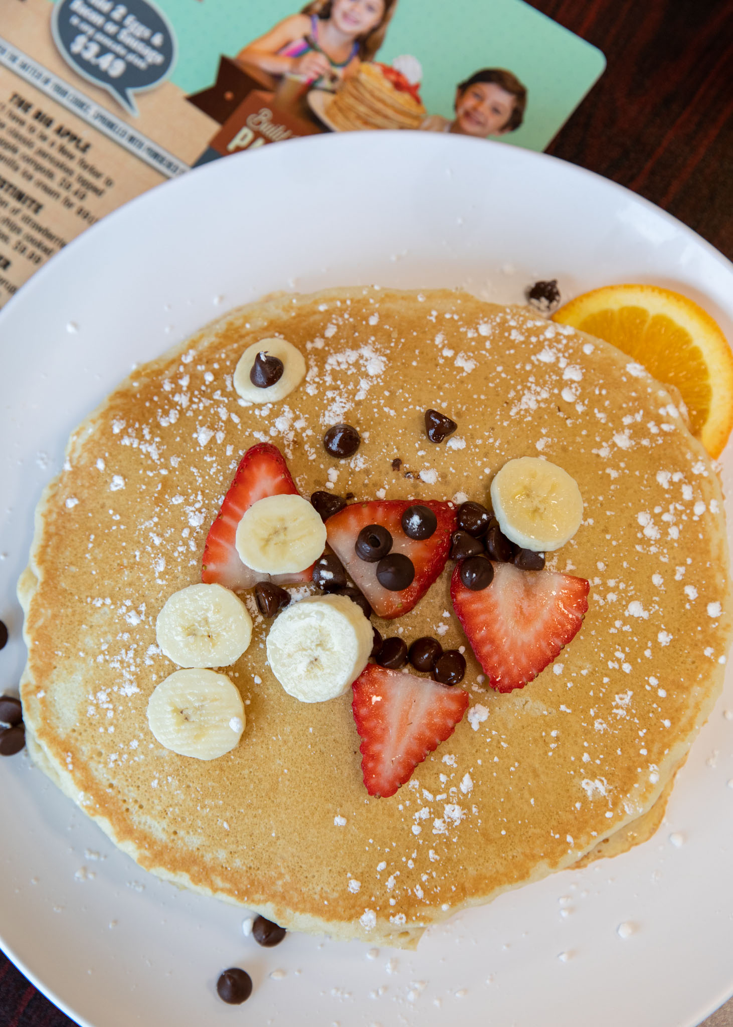 Pancake decorated with banana slices, strawberries, and chocolate chips