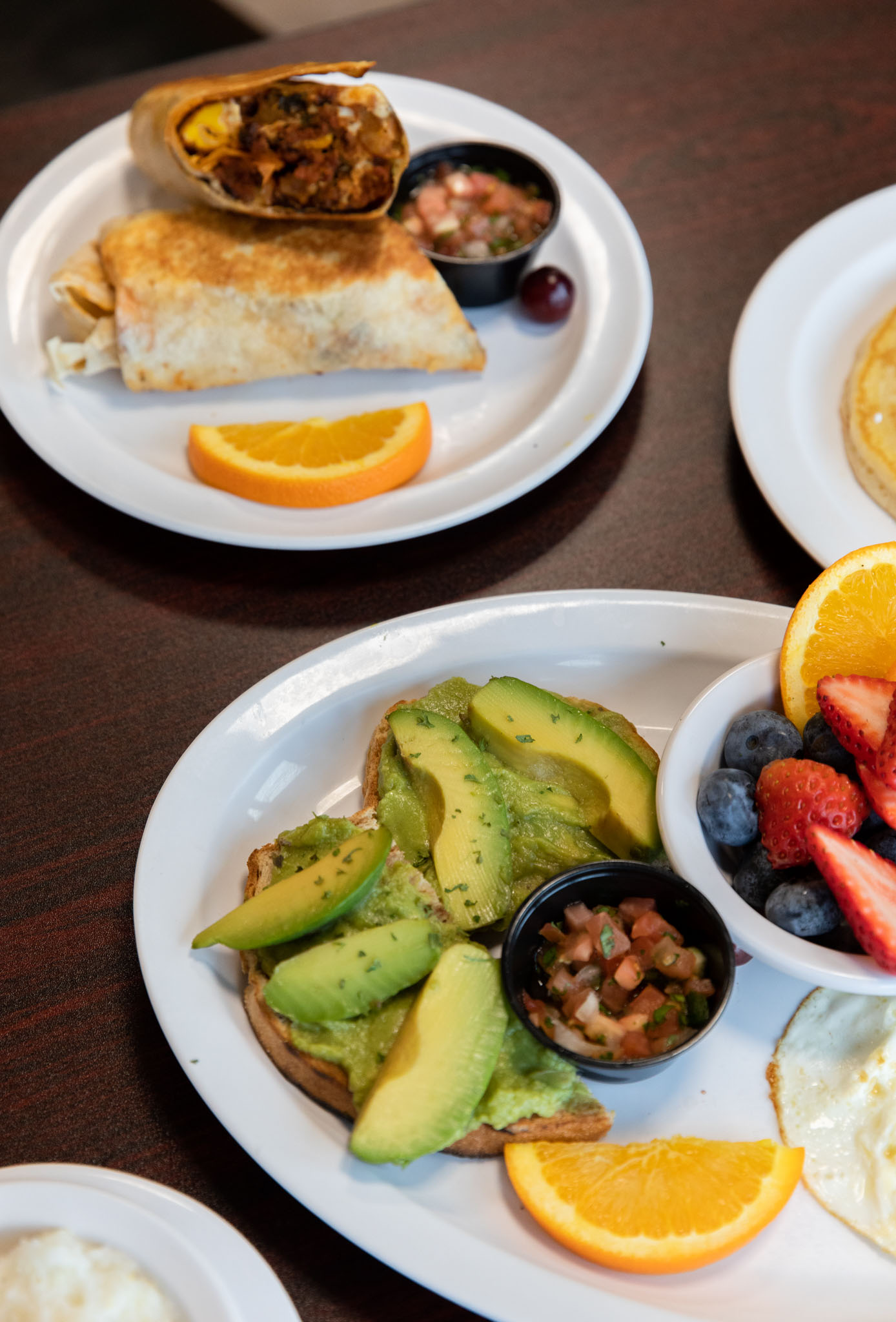 Two breakfast plates featuring avocado toast with sliced avocado