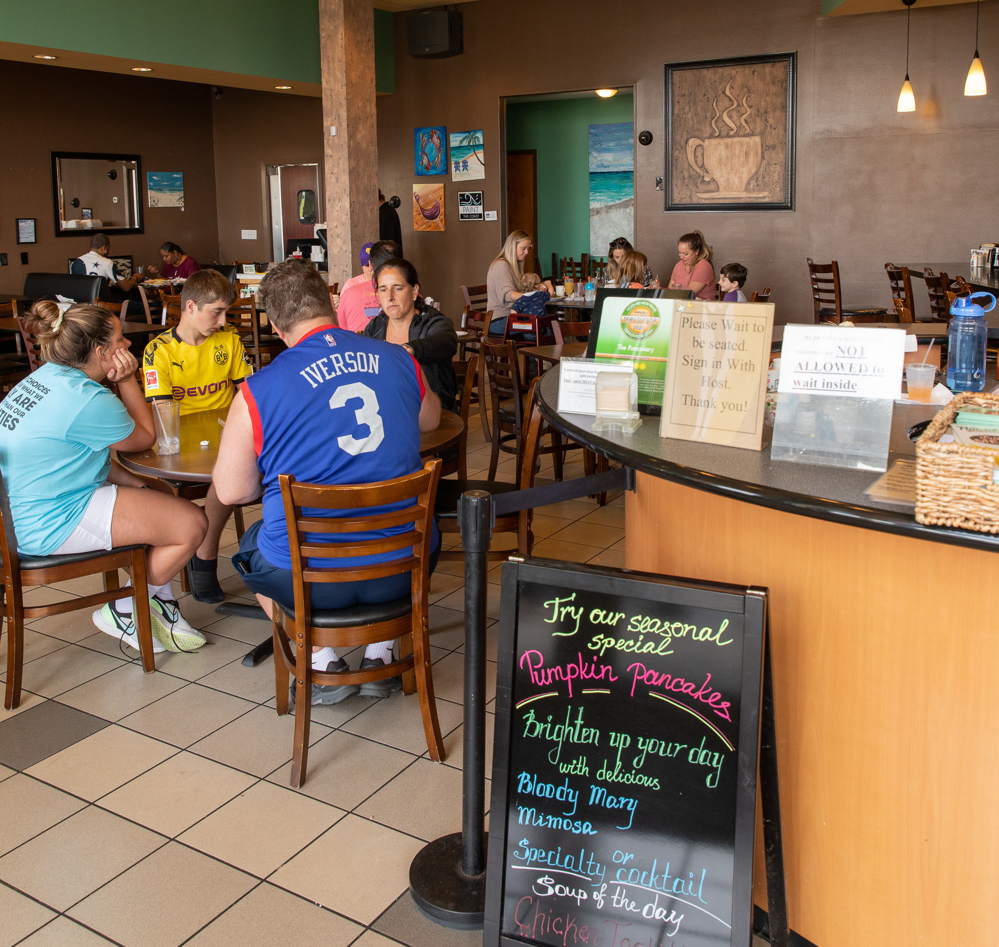 A lively café interior with multiple groups of people seated at tables