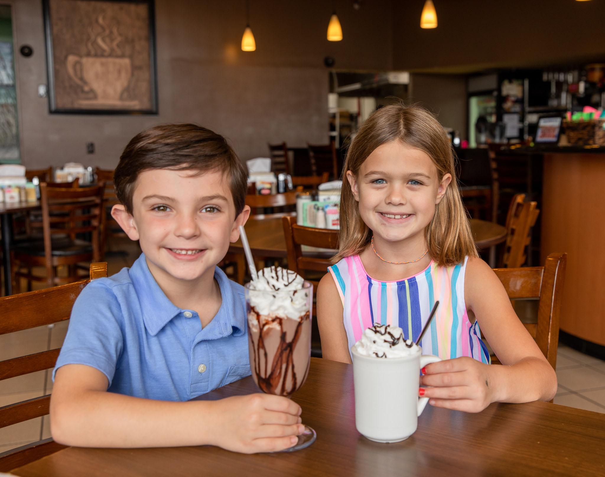 Kids and their chocolate drink with whipped cream and chocolate drizzle