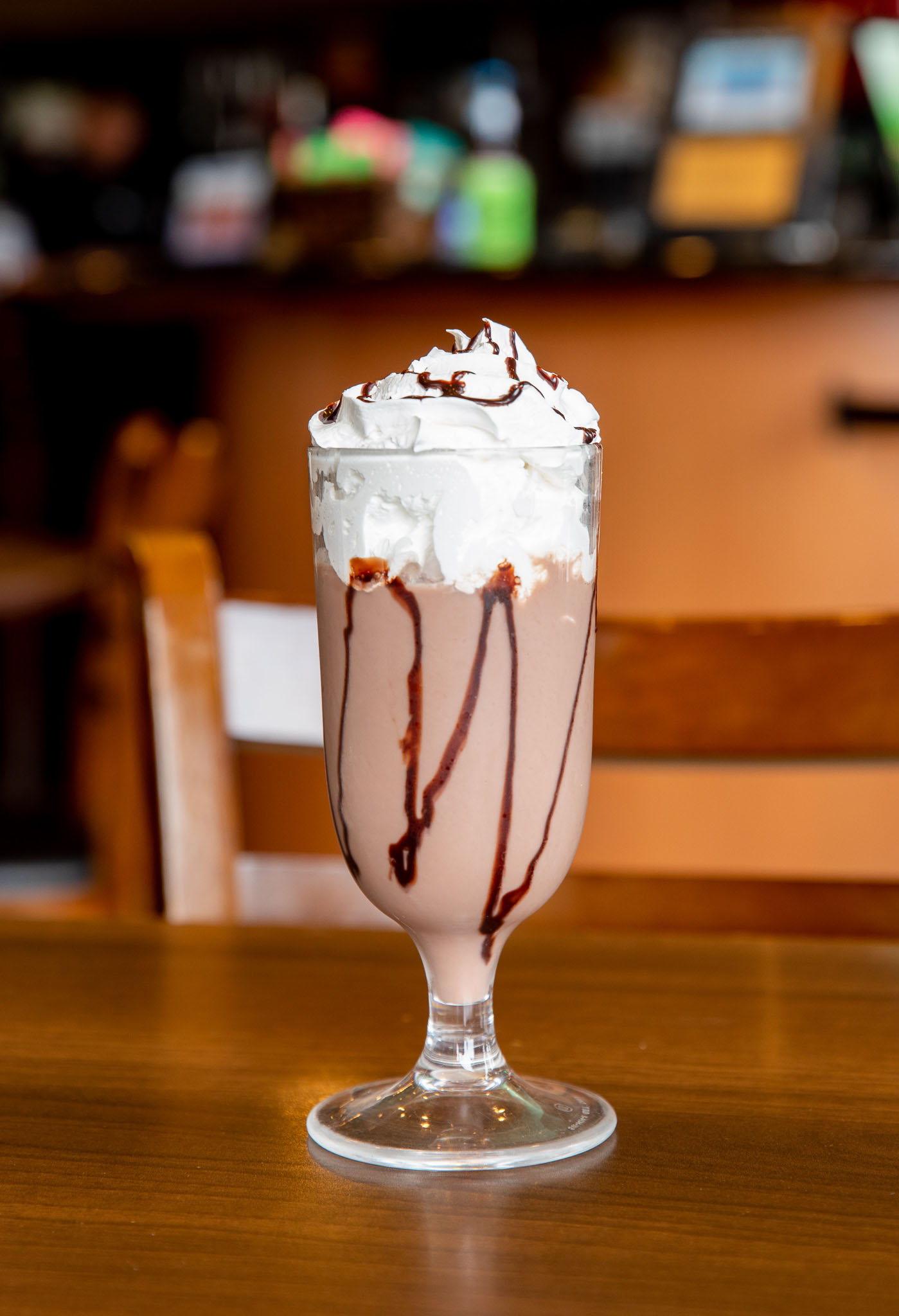 Chocolate milkshake topped with whipped cream and drizzled chocolate syrup