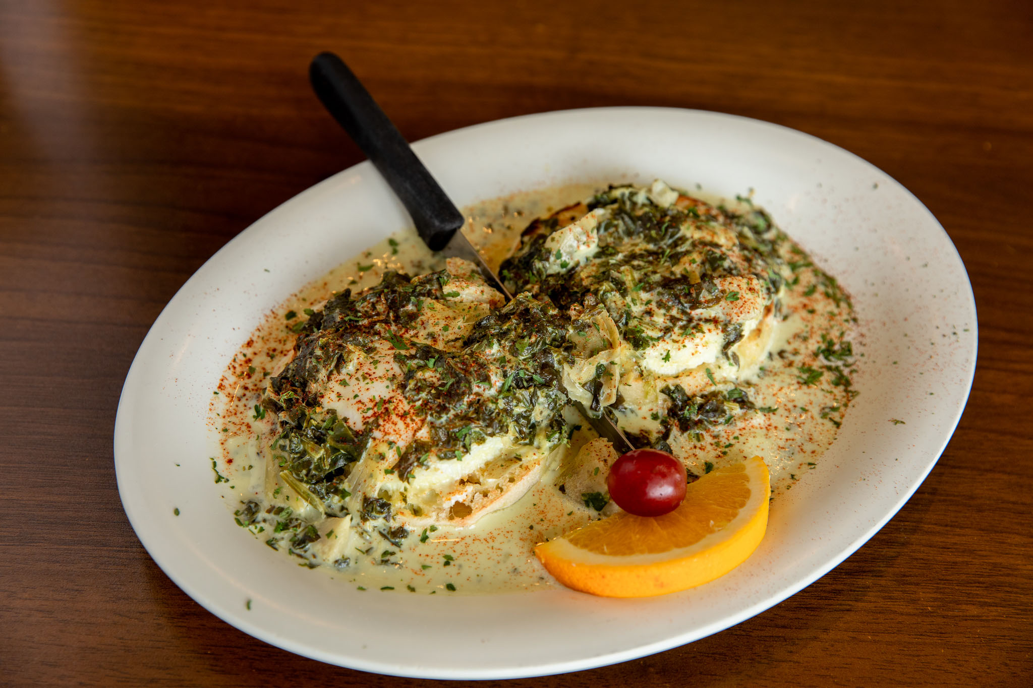 Savory eggs benedict topped with creamy spinach and herb sauce at The Pancakery
