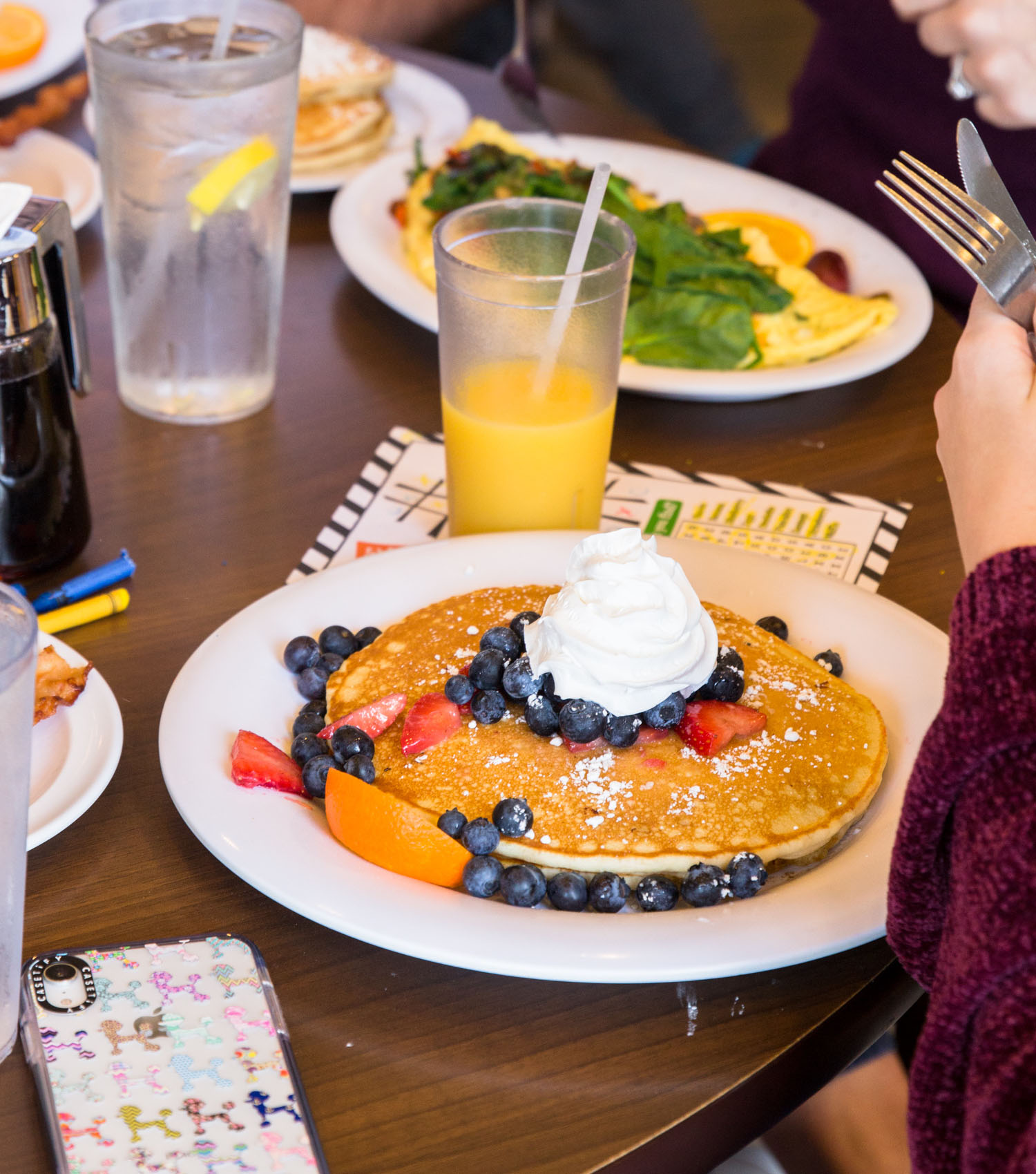 A plate of golden pancakes topped with blueberries, strawberries, whipped cream