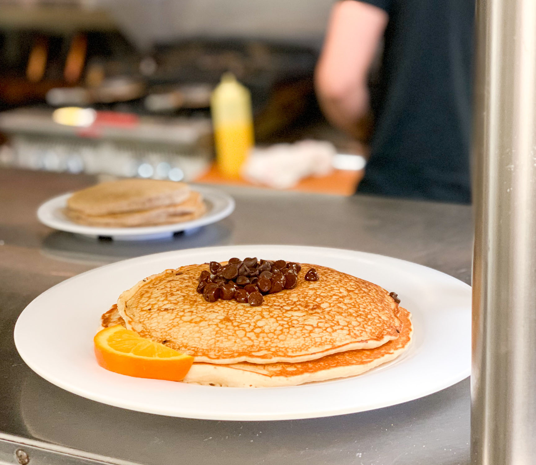 Two golden brown pancakes stacked and topped with a handful of chocolate chips