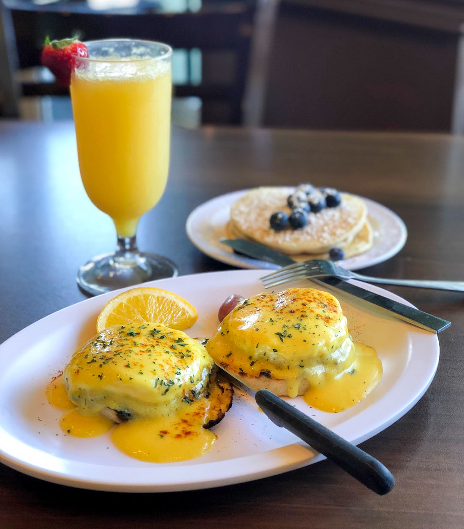 A lively breakfast restaurant with guests seated at various tables enjoying their meals.